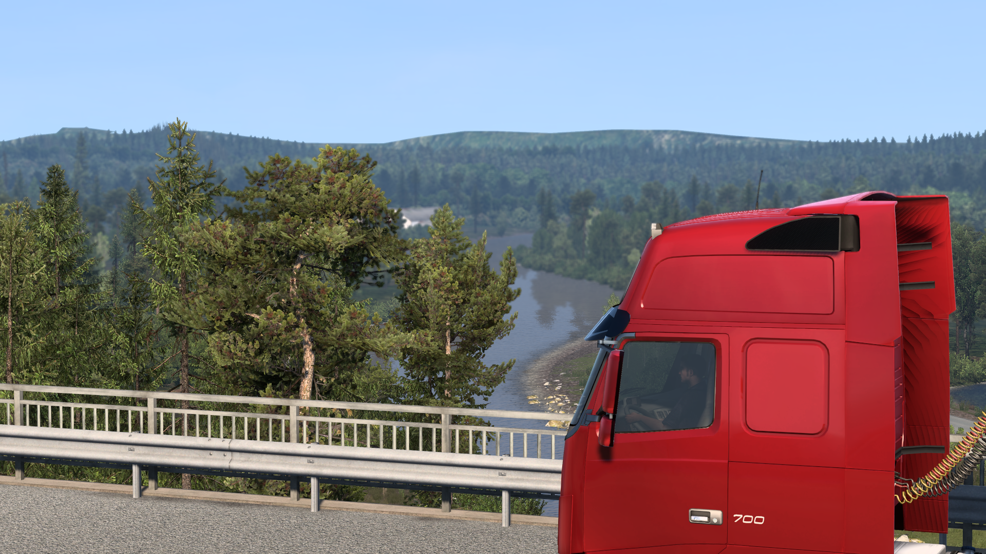 Brücke über Flusslauf mit Lkw und bewaldeter Hügellandschaft